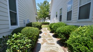 A pathway between two white buildings with stone steps and trimmed bushes. - Magnolia Gardens NEW (Grovetown)