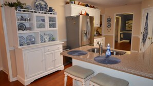A kitchen with white cabinets, a stainless steel refrigerator, a granite countertop, and a sink. - Magnolia Gardens NEW (Grovetown)