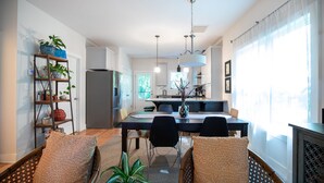 A modern kitchen with a dining area, featuring a central island, pendant lighting, and a view of the outdoors. - Game day 3/2. 5 in charming Watkinsville downtown! (Watkinsville)