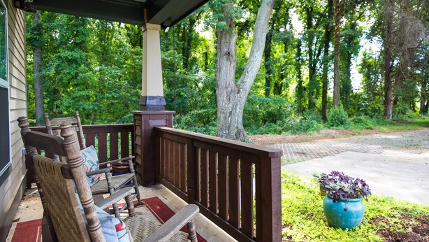 A porch with a wooden bench and a potted plant. - Game day 3/2. 5 in charming Watkinsville downtown! (Watkinsville)