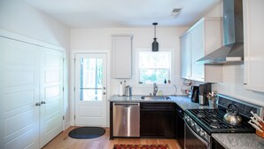 A modern kitchen with white cabinetry, a stainless steel dishwasher, a gas stove, and a window providing natural light. - Game day 3/2. 5 in charming Watkinsville downtown! (Watkinsville)