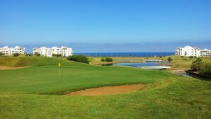 Een golfbaan met bunkers, een vijver en een vlag.