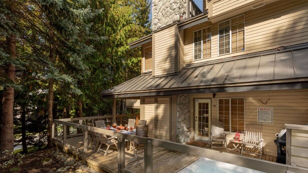 A wooden deck with outdoor seating, a hot tub, and a stone chimney. - Ski to the door!True SI/SO Luxury 2BrTH-Private HT (Whistler)
