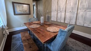 Une salle à manger avec une table en bois, des chaises recouvertes d’un tissu bleu et un lustre.