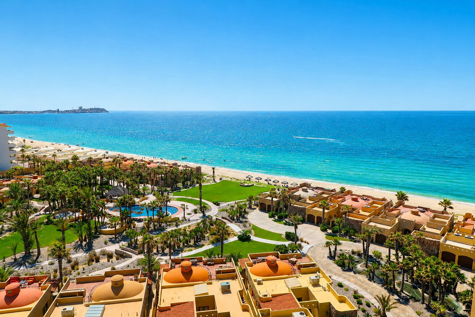 A resort with a pool, palm trees, and a beach view.