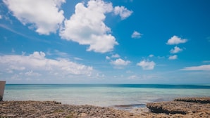 Ein felsiger Strand mit klarem türkisblauem Wasser und einem wolkenlosen, strahlend blauen Himmel.