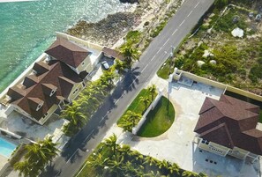 Vista aérea de una propiedad costera con varias edificaciones, una carretera y una playa.