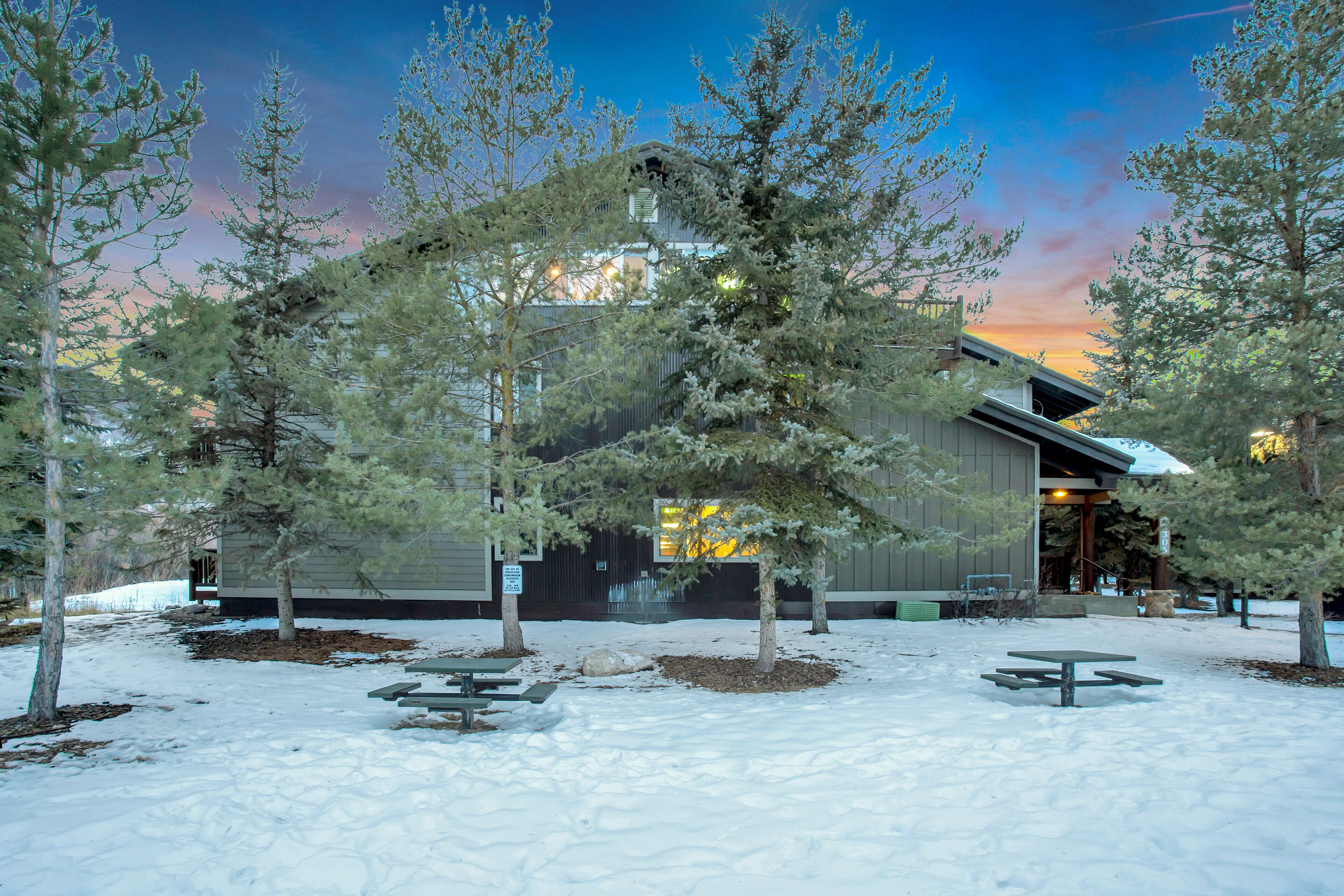Un edificio con un espacio exterior techado, rodeado de árboles y nieve.