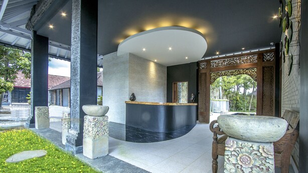 A reception area with a modern design, featuring a reception desk, decorative stone elements, and a seating area with a carved wooden bench.