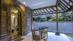A dining area with a table and chairs, a large ornate mirror, and a view of the garden.