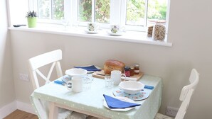 Ein Esstisch, gedeckt mit Brot, Marmeladengläsern und einer Tasse.