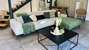 A modern living room with a grey sofa, black coffee table, and a wooden staircase. - New villa 185m2 located close to beaches, port and city center (Porto-Vecchio)