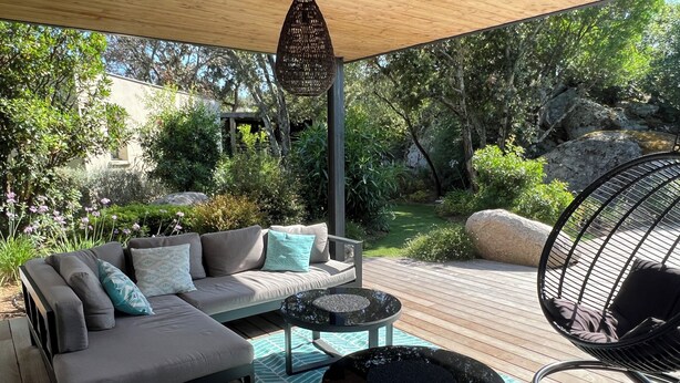 An outdoor patio with a sofa, round tables, and a hanging chair. - New villa 185m2 located close to beaches, port and city center (Porto-Vecchio)