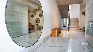Un interior moderno con un espejo circular grande, un banco de madera y una escalera.