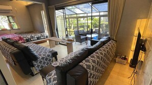 Un espacio habitable compacto con sofá, una mesita y una silla. Una ventana grande ofrece vistas al exterior.