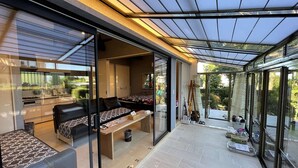 Un espacio habitable moderno y de planta abierta con un patio cubierto de cristal, un conjunto de sofás y una mesa de comedor.