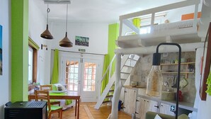 Een ruime woonkamer met een bank, eettafel en keukenhoek.