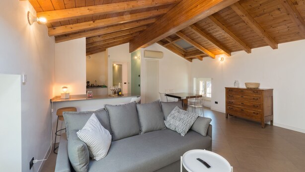 Un salon chaleureux avec un canapé gris, une petite table d’appoint blanche et un meuble en bois.