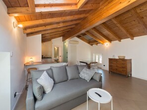 Uma sala de estar aconchegante com um sofá cinza, uma pequena mesa lateral branca e um armário de madeira.