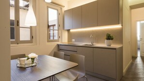 Et moderne køkken med spiseplads, med en indbygget vask, hængende lamper og en potteplante på disken.