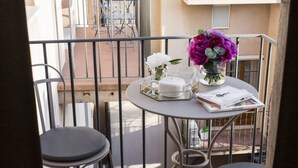 En balkon med et bord, en blomstervase, en tepotte og en bog.