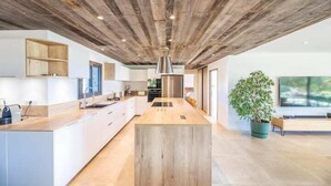 Una cocina moderna con techo de madera, muebles blancos y una isla central.
