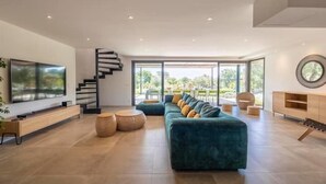 Una sala de estar moderna con un sofá grande, un televisor y una escalera.