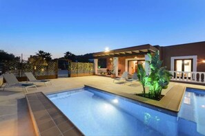 A swimming pool with lounge chairs and a covered patio area.