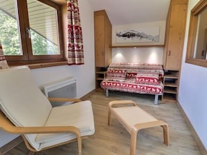A cozy room with a wooden-framed sofa, a cushioned chair, and a small table.