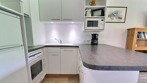 A kitchen with white cabinets, a microwave, a coffee maker, and a wooden floor. - Bright 2-Rooms on Slopes, Near Shops, South Balcony (Méribel)