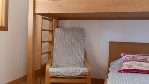 A bunk bed with a wooden ladder, a single bed with patterned bedding, and a chair with a patterned cushion. - Bright 2-Rooms on Slopes, Near Shops, South Balcony (Méribel)