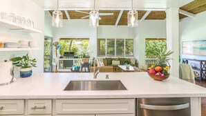 A modern kitchen with a large island, stainless steel appliances, pendant lighting, and a view to an outdoor patio area.