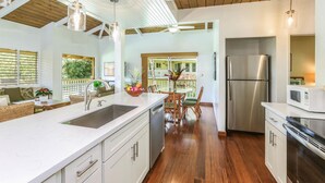 A modern kitchen with a large island, stainless steel appliances, and a view to a balcony.