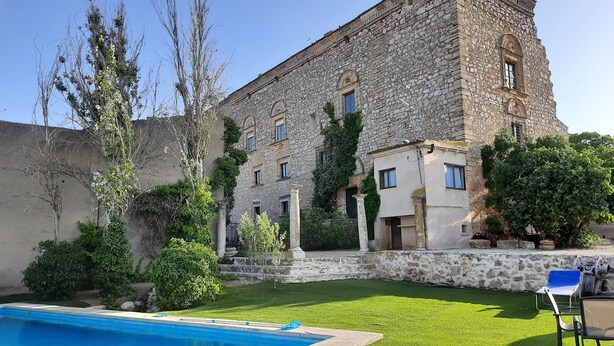Un bâtiment en pierre doté d’une piscine et d’une pelouse verdoyante.