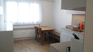 A compact kitchen with a dining area, a window with curtains, and a built-in oven. - Sunnmatt 752 Appartement/Fewo 3-Bettwohnung by Interhome (Engelberg)