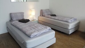 Two single beds with patterned bedding, a bedside lamp, and a mirror on the wall. - Sunnmatt 752 Appartement/Fewo 3-Bettwohnung by Interhome (Engelberg)