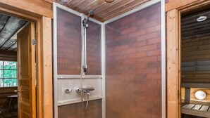Una cabaña de madera con cabina de ducha, una puerta y un banco.
