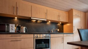 A modern kitchen with wooden cabinets, a built-in oven, a coffee maker, and a sink.