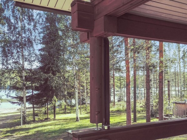 A covered outdoor area with a view of a forest and a body of water.