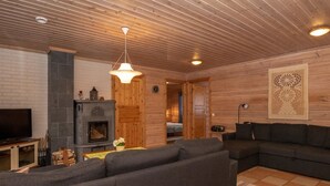 Una sala de estar acogedora con chimenea, un sofá, un televisor y techo de madera.
