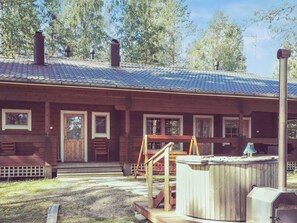 Eine Holzhütte mit Veranda, Whirlpool und einer Leiter.