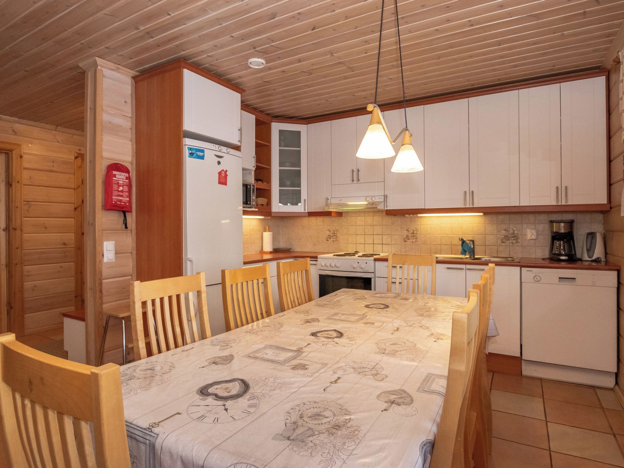 Cocina compacta con armarios de madera, una mesa de comedor con mantel de reloj y un lavavajillas empotrado.