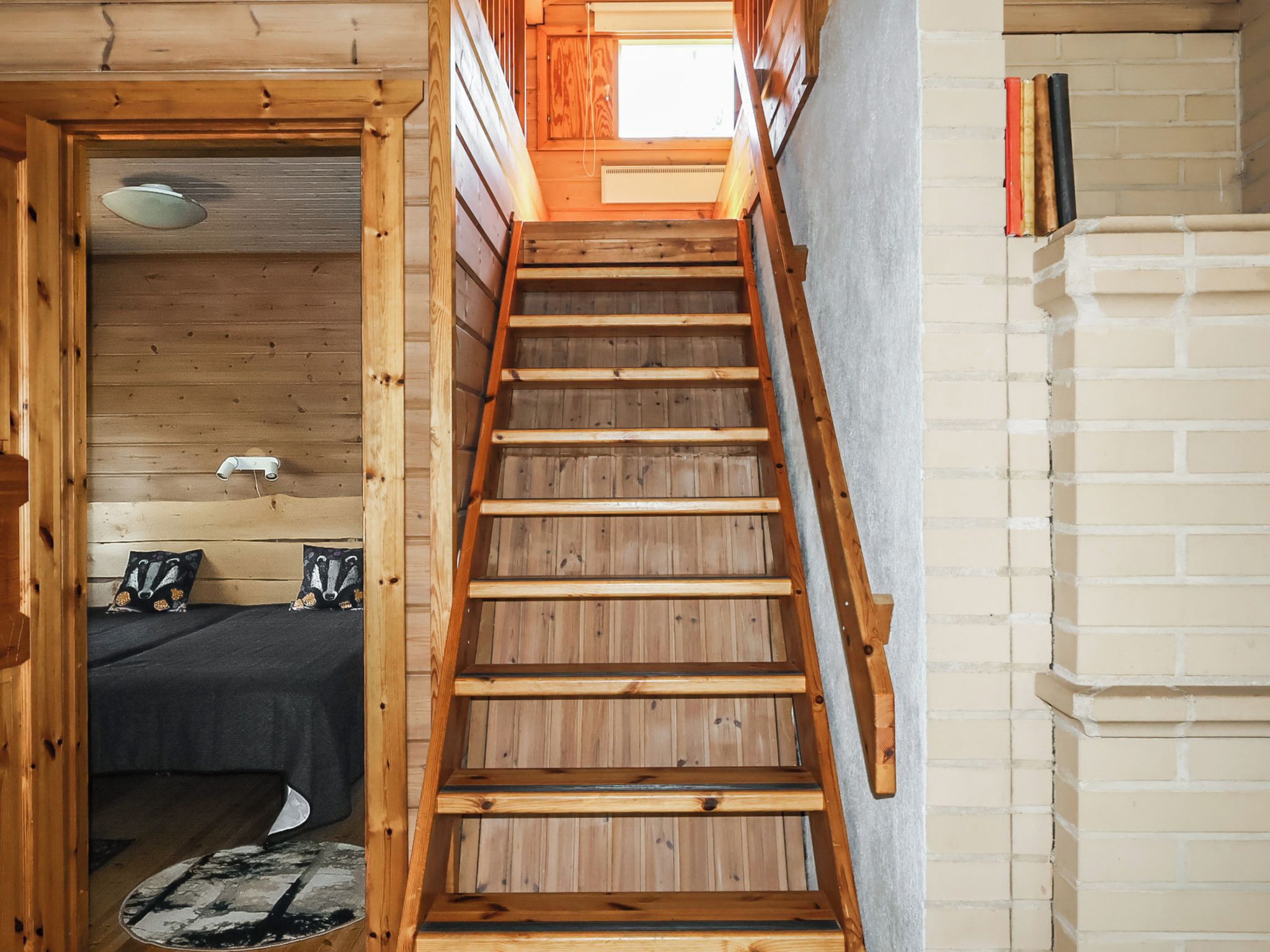 A wooden staircase leading to a loft bedroom with a skylight.