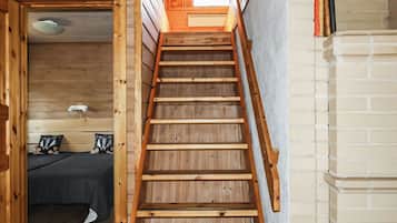 A wooden staircase leading to a loft bedroom with a skylight.