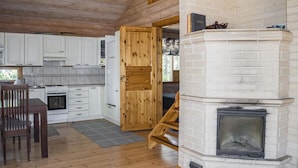 A wooden cabin interior with a kitchen, dining area, and a fireplace. - Leijankorpi by Interhome (Pöytyä)