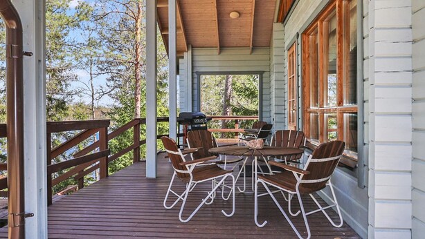 A covered outdoor deck with wooden furniture and a grill. - Leijankorpi by Interhome (Pöytyä)