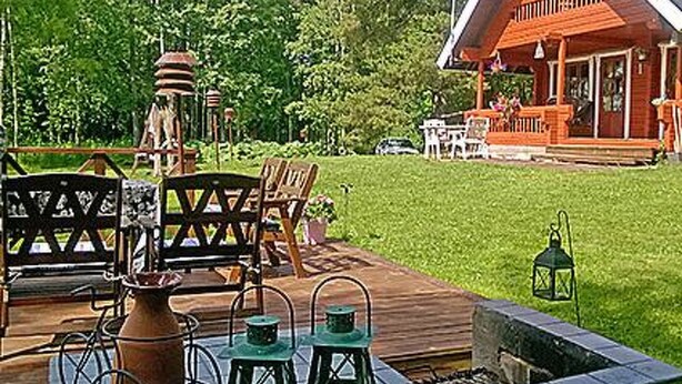 A wooden deck with outdoor furniture, a fire pit, and a rustic building in the background.