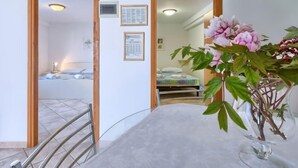 Habitación de hotel con una cama, un escritorio y un florero con flores. Hay diplomas enmarcados en la pared.
