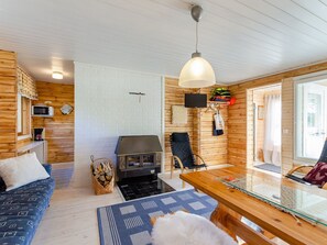 A cozy cabin interior with a fireplace, wooden walls, a dining table, and a seating area. - Jussinlahti, vaikon loma 6 by Interhome (Kaavi)
