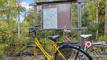 A wooden sign with 'KAREN KOSKI' and a map, two bicycles, and a forested area.
